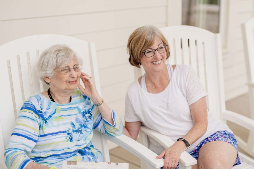 Senior woman and adult woman seated in chairs on patio